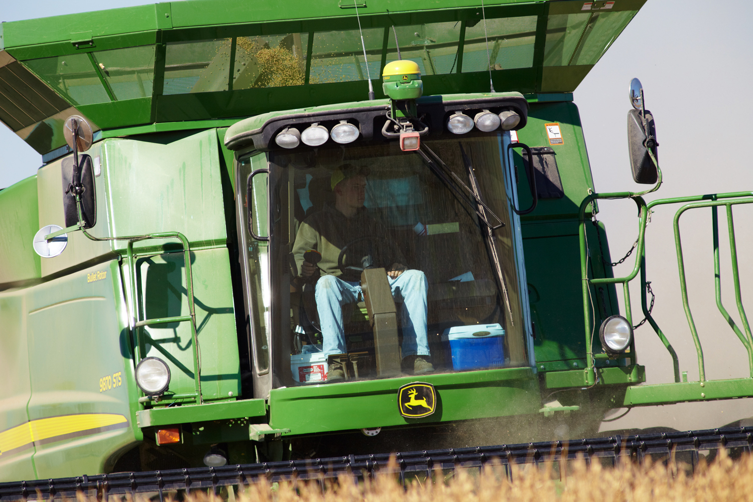 A young farmer at the controls of his John Deere combine