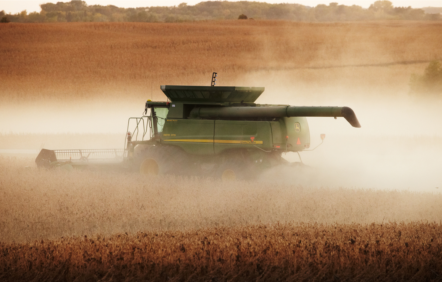 A John Deere combine amid a dust cloud in a soybean field in Minnesota