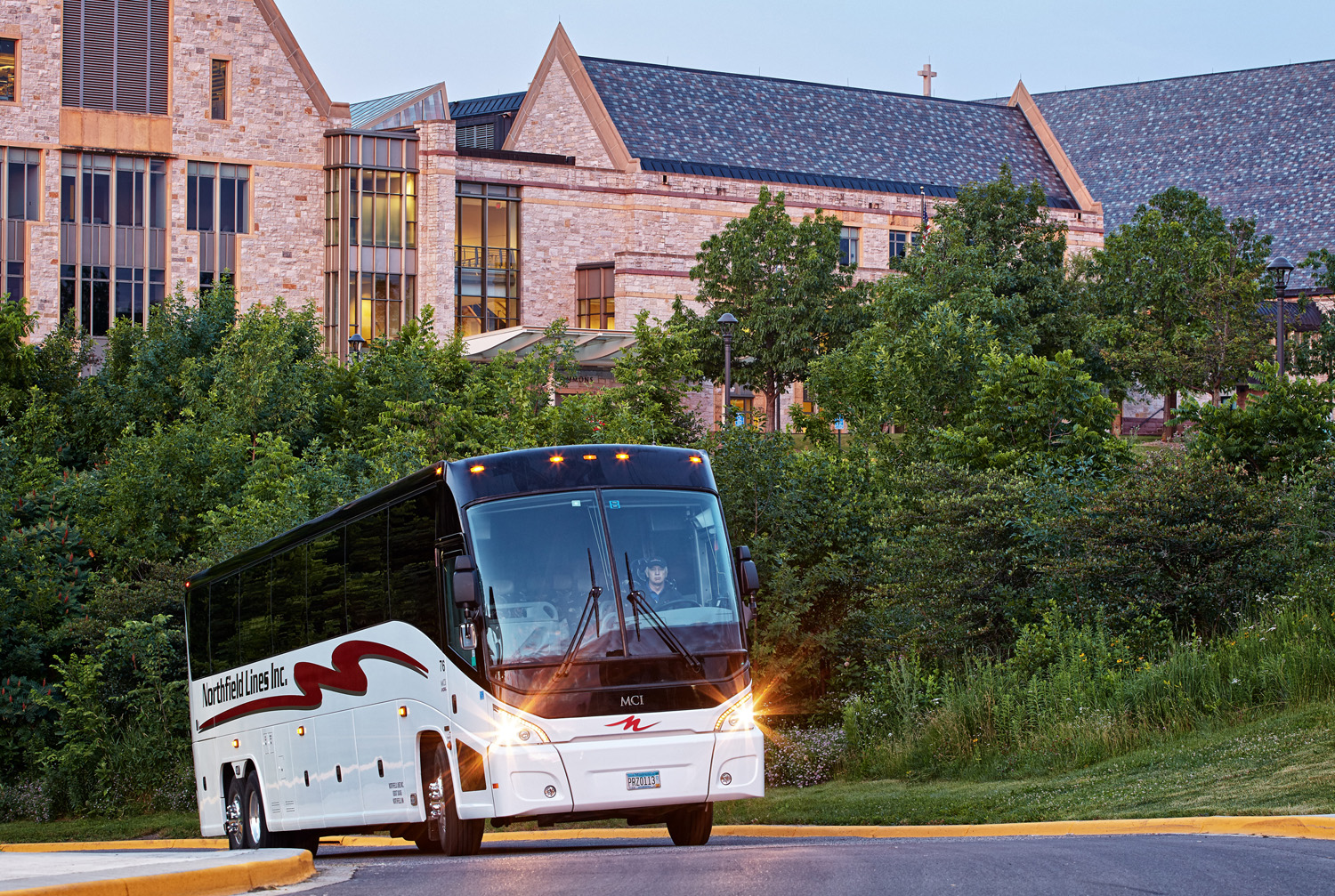 An MCI motor coach ascends the driveway of St. Olaf College in Minnesota.