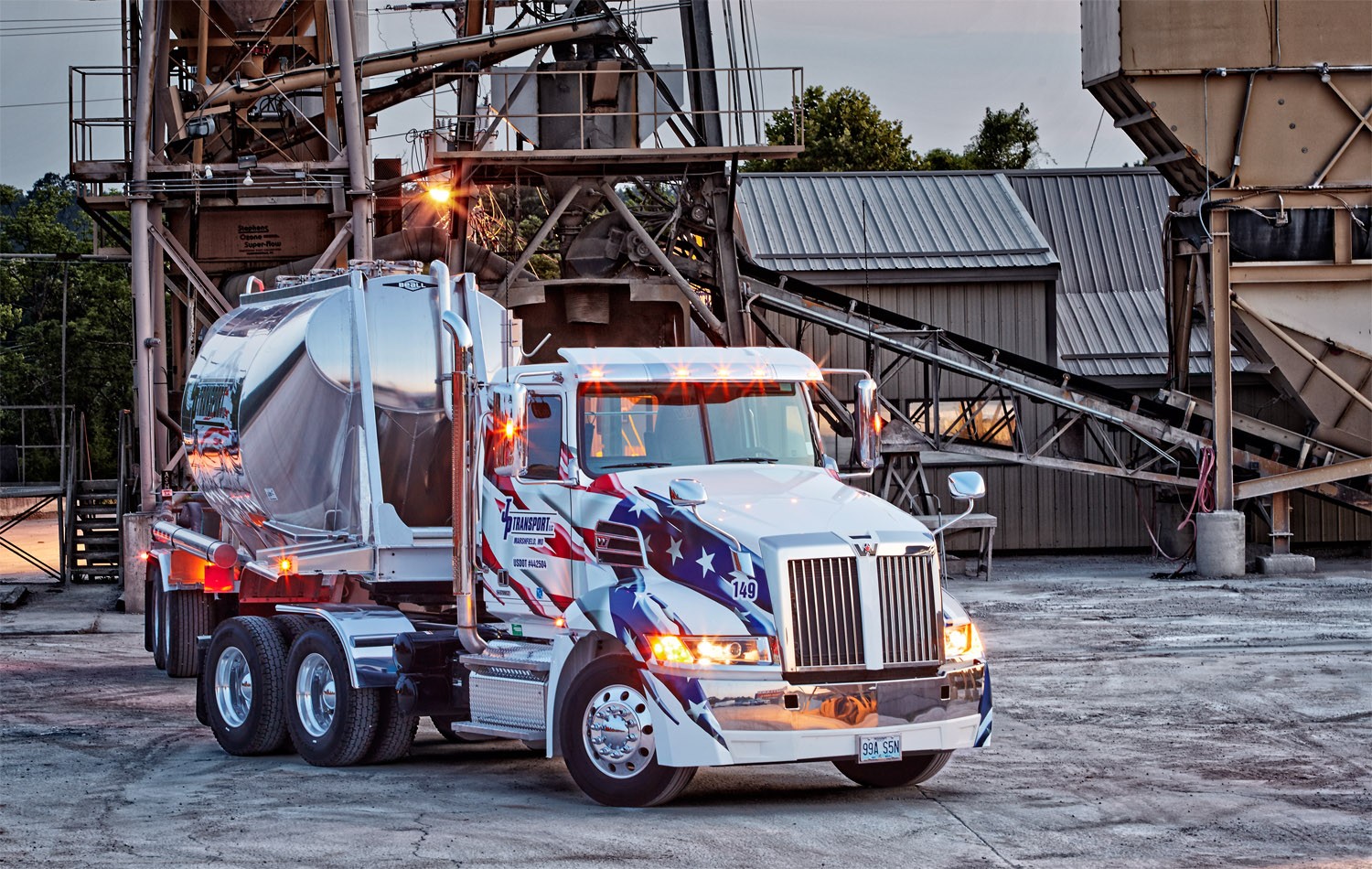 A patriotic themed Western Star 4700 and pneumatic tank trailer parked at a ready-mix plant