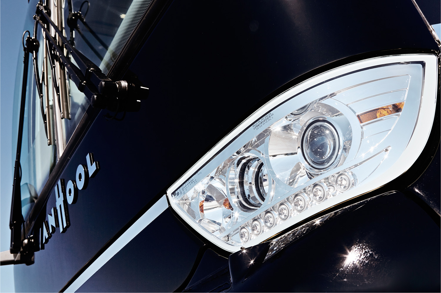 The headlights and branding of a Van Hool motor coach.